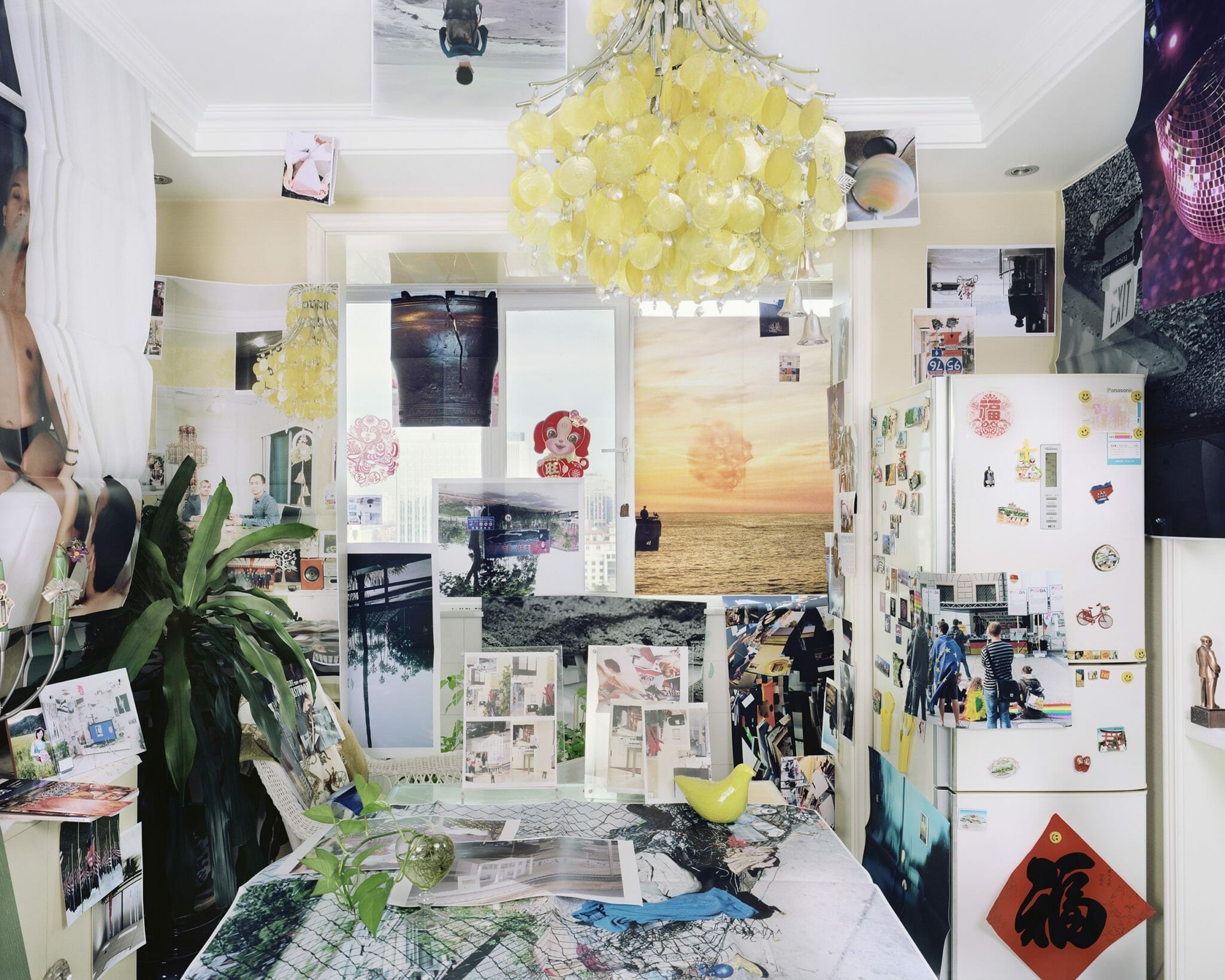 photograph showing an interior kitchen or dining space covered in printed photographs