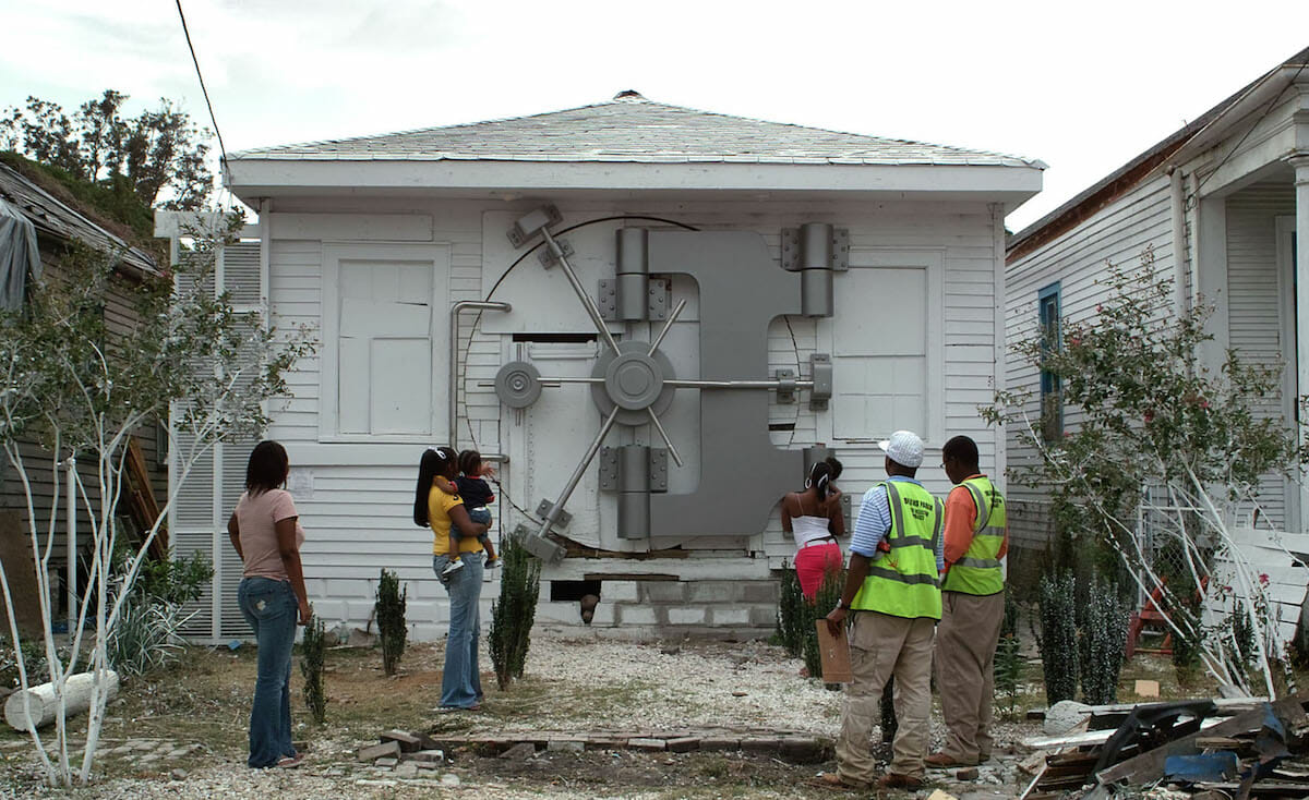 photograph showing people standing in front of a house or building with a bank vault opening