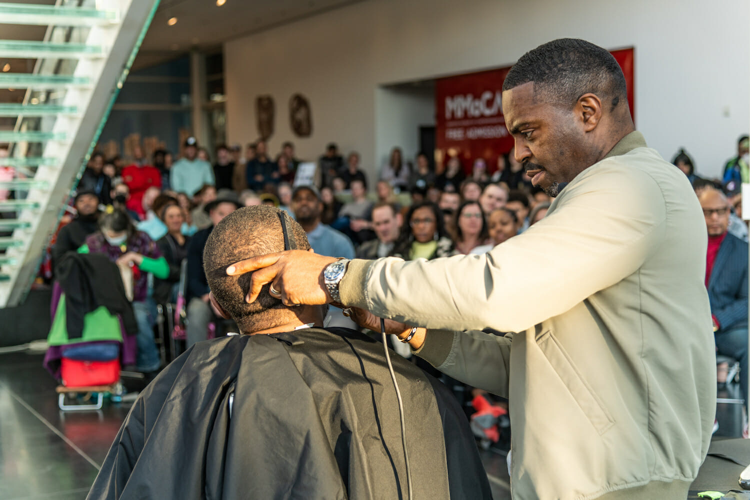 Artist Faisal Abdu'Allah cutting Ron Dayne's hair in front of an audience.