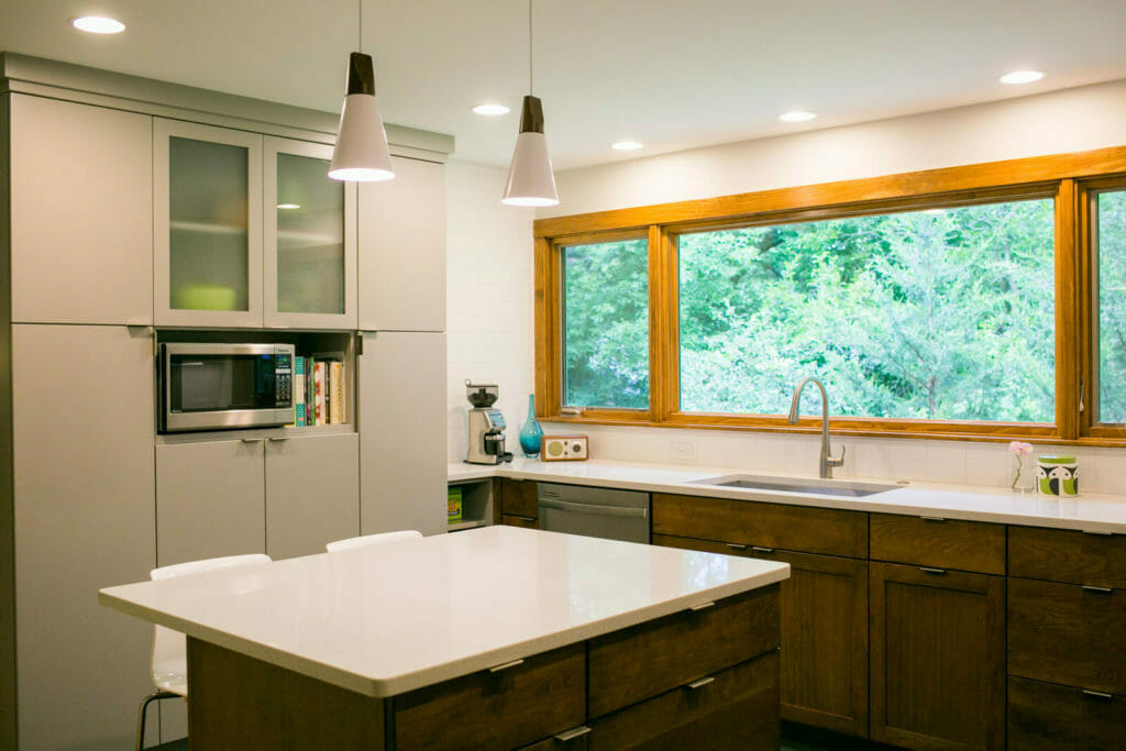 Quartz countertops, Woodharbor painted and walnut cabinets, with modern accents, create a fresh kitchen remodel by TDS Custom Construction.